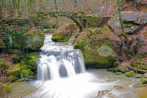 a bridge over a stream with a waterfall at Room in Farmhouse Berkel in Bockholtz