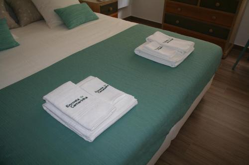 two white towels are sitting on a bed at Encosta da Camarinha in Ferreira do Zêzere