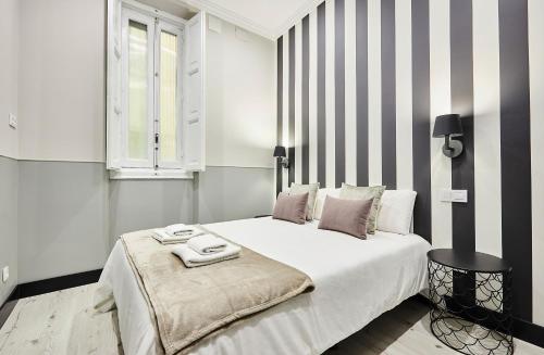 um quarto com uma grande cama branca com paredes listradas em SERRANO GOLDEN MILE II, by Presidence Rentals em Madri