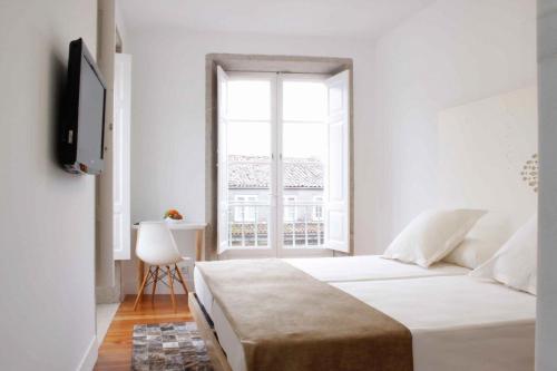a white bedroom with a bed and a window at Hotel Pazo de Altamira in Santiago de Compostela