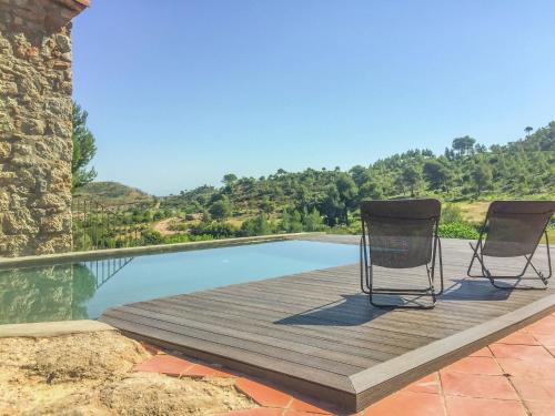 Castellolí的住宿－Belvilla by OYO Cal Sant Miquel，游泳池旁的木甲板上摆放着两把椅子