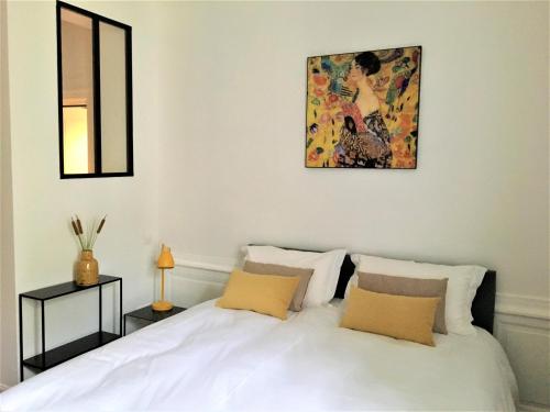 a bedroom with a white bed and a painting on the wall at Le Duplex des Eclusiers in Redon