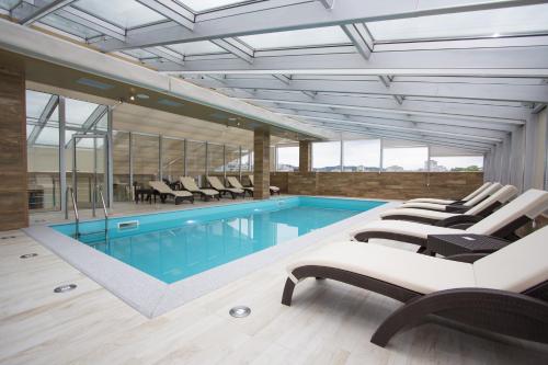 a pool in a house with lounge chairs and a swimming pool at Hotel Talija in Banja Luka