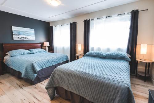 a bedroom with two beds and a window at Hotel Le Plaza in La Baie