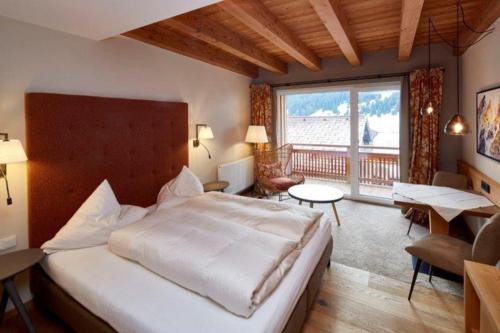 a bedroom with a large bed and a large window at Alpenjuwel Rohnenspitze in Zöblen