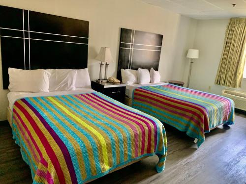 a hotel room with two beds with colorful blankets at Tappan Zee Hotel in West Nyack