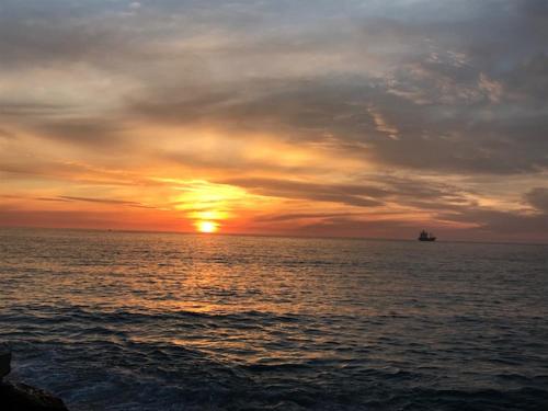 a sunset over the ocean with a ship in the distance at Una vista increíble al Pacifico in Concón