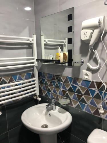 a bathroom with a sink and a hair dryer on the wall at Wander Kazbegi Hotel in Stepantsminda