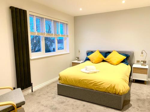 a bedroom with a bed with yellow pillows and a window at Stylish Cambridge Pad in Bar Hill