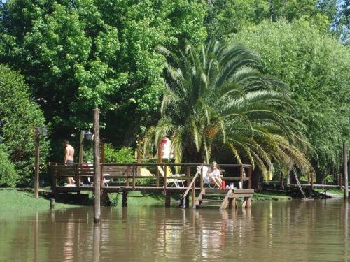 a palm tree and people sitting on a dock in a river at Ensueño casa de isla in Tigre