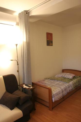 a bedroom with a bed and a chair and a lamp at STUDIO APARTMAN MARIA in Čavle