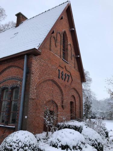 a red brick building with snow on it at De Pannenbakkerij in Kruishoutem