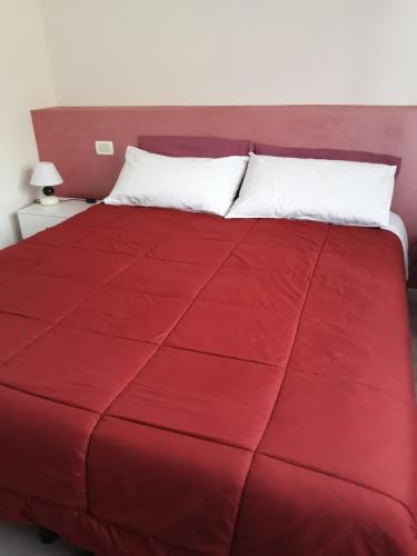 un letto rosso con cuscino bianco e piumone rosso di B&B A Un Passo Da a Casale sul Sile