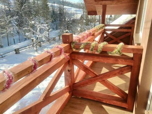 a wooden fence with flowers on it in the snow at Садиба у Насті in Nizhniy Studenyy