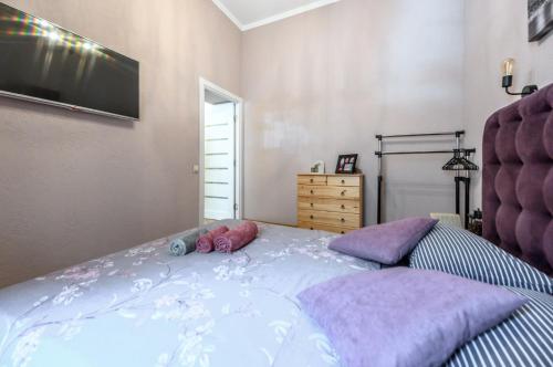 - une chambre avec un lit doté d'oreillers violets et une télévision dans l'établissement Тихие апартаменты недалеко от Дерибасовской, à Odessa