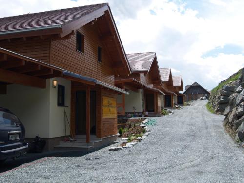 a row of wooden houses on a dirt road at Mathiasl Wellness-Ferienhäuser in Bodensdorf