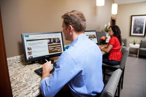 a man sitting at a desk with a computer at Staybridge Suites - Denton by IHG in Denton
