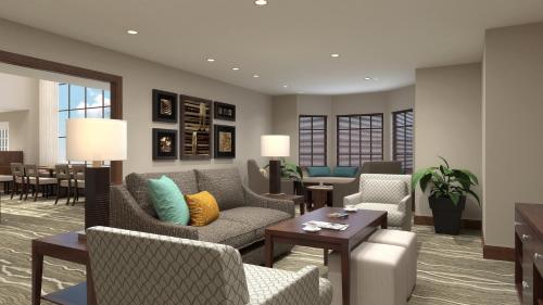 a living room with couches and chairs and tables at Staybridge Suites - Denton by IHG in Denton