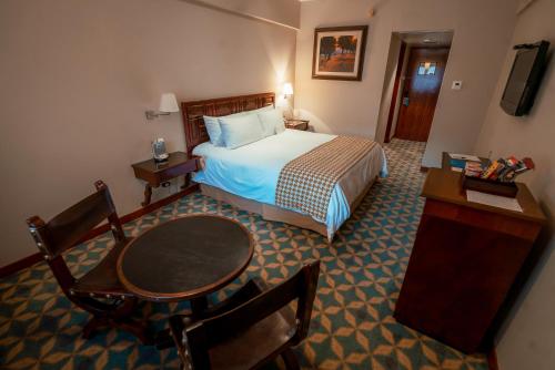 
a hotel room with a bed, table and chairs at Costa del Sol Trujillo Centro in Trujillo

