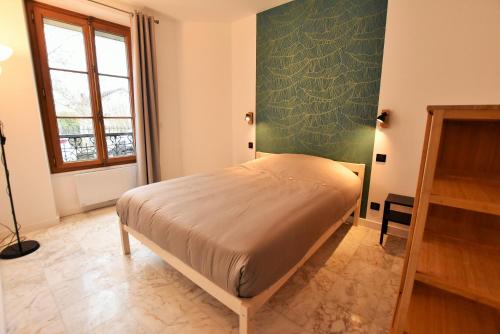 uma cama num quarto com uma parede verde em LE COTTAGE AUVERSOIS - Rdc -T2 - em Auvers-sur-Oise