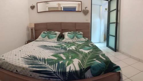 een slaapkamer met een bed met een groene plant erop bij Le Pélikan in Le Gosier