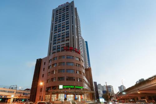 a tall building on a city street with traffic at Holiday Inn Express Shanghai Zhenping by IHG in Shanghai