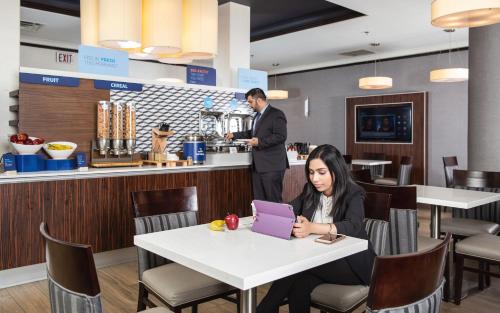 a woman sitting at a table in a restaurant with a laptop at Holiday Inn Express Edmonton Downtown by IHG in Edmonton