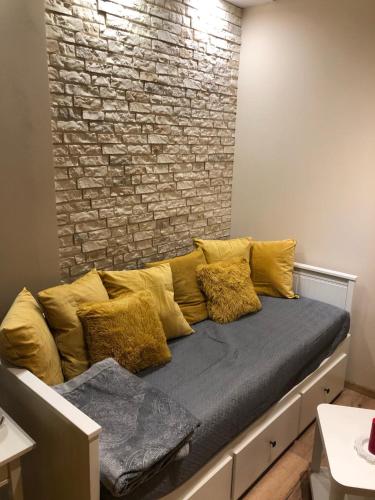un sofá con almohadas amarillas en una habitación con una pared de ladrillo en Nowoczesny pokój w spokojnej okolicy, en Chełmno