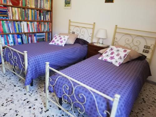 two beds in a room with bookshelves at Pratomagno Apartment in Cetica