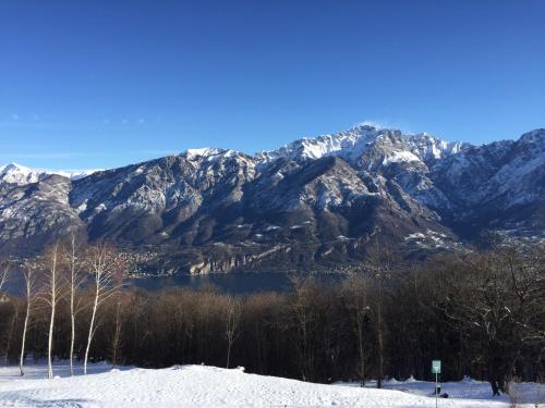 a snow covered mountain range with a lake and trees at Casa Grazia in Magreglio
