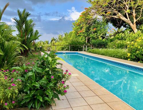 una piscina en un jardín con flores en Palmlea Farms Lodge & Bures - Villas, en Vatutandova