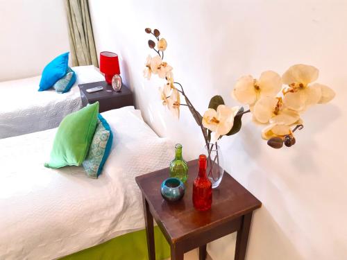 una habitación con 2 camas y una mesa con un jarrón con flores en Departamento Encantador monoambiente Domaine Laborde I en Mendoza