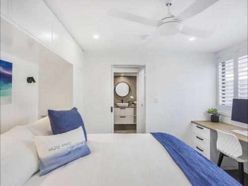 a white bedroom with a bed and a desk at Kirra Waves in Gold Coast