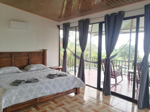 a bedroom with a bed and a balcony with sliding glass doors at Hotel Cabinas Murillo in Drake