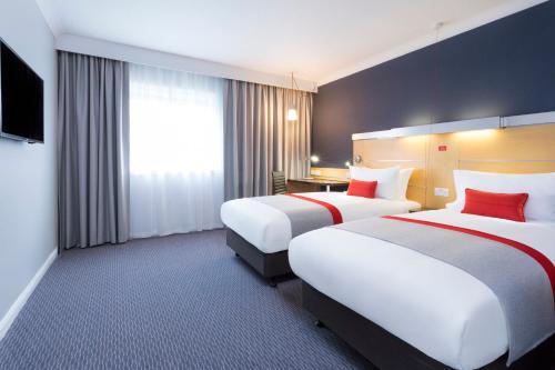 um quarto de hotel com duas camas e uma televisão em Holiday Inn Express Park Royal, an IHG Hotel em Londres