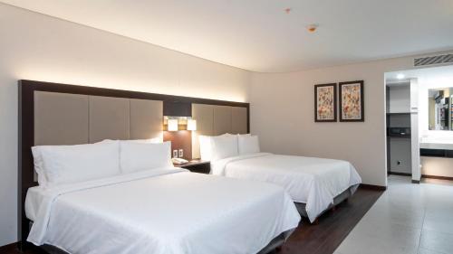 a hotel room with two beds with white sheets at Holiday Inn Express - Mexico Basilica by IHG in Mexico City