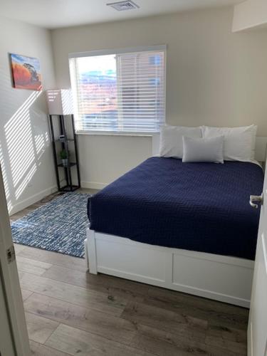 a bedroom with a bed with a blue blanket and a window at Moab Redcliff Condos in Moab