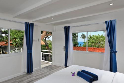 a bedroom with blue curtains and a bed with a view of the ocean at Kata White Villas in Kata Beach