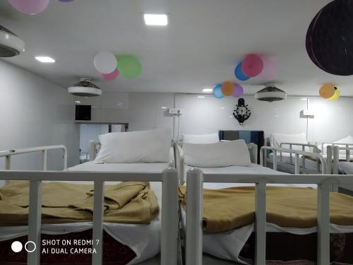 Star Dormitory في مومباي: سريرين في غرفة مستشفى مع البالونات على الحائط