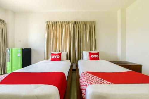 2 posti letto in una camera con lenzuola rosse e bianche di OYO 350 Mae Saeng Place a Si Racha