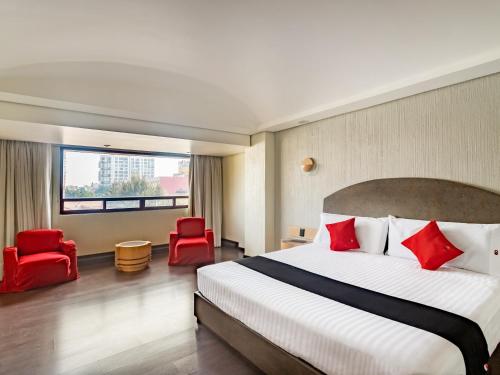 a hotel room with a bed and two red chairs at Capital O Andrade, Mexico City in Mexico City