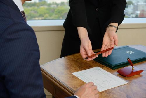 a woman standing at a table holding a pen at Rihga Royal Hotel Hiroshima in Hiroshima