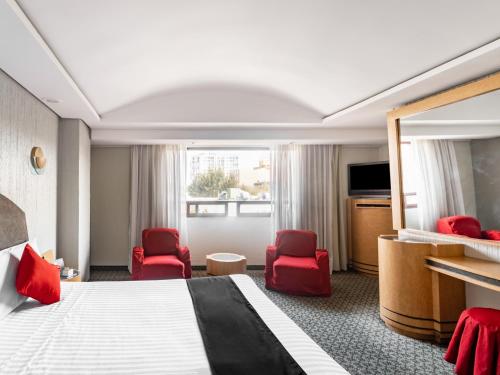 a hotel room with a bed and red chairs at Capital O Andrade, Mexico City in Mexico City