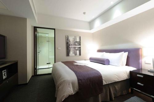a hotel room with a large bed and a television at K Hotel - Yunghe in Yonghe
