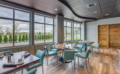 a restaurant with tables and chairs and windows at Holiday Inn & Suites Bellingham by IHG in Bellingham