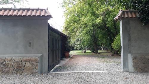 a gate to a building with a dirt road at La casita en el parque in Chacras de Coria