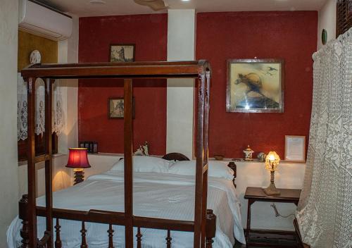 a bedroom with a canopy bed and red walls at The Ferreiras in Mumbai