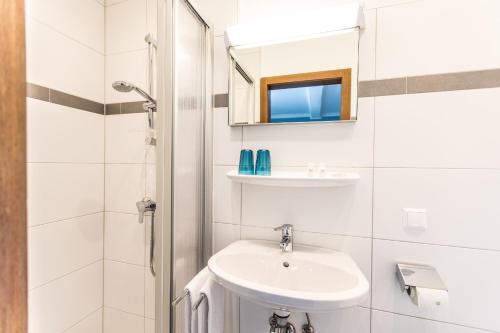 Baño blanco con lavabo y espejo en Best In Hosting Beach House Velden, en Velden am Wörthersee