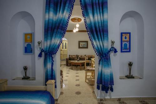 Cet appartement comprend une chambre dotée de rideaux bleus et un salon. dans l'établissement Dar Sidi Mfedal, à Chefchaouen