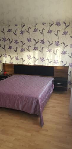 Un dormitorio con una cama morada y una pared con flores púrpuras. en Ahtme apart, en Kohtla-Järve